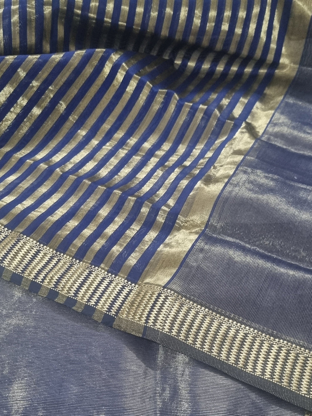 Close-up of royal blue Maheshwari handwoven silk fabric with gold Zari border and motifs