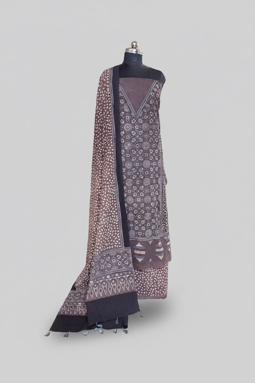 Brown Ajrakh cotton 3-piece unstitched suit set displayed on mannequin — kurta with circular block print, dupatta with tassel border, and dark bottom fabric