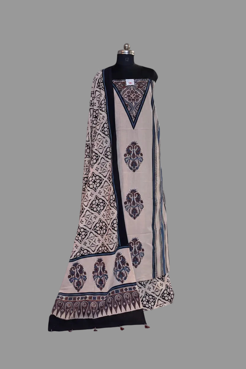 Oatmeal and blue Ajrakh cotton 3-piece unstitched suit set on mannequin — cream kurta with blue and red paisley medallion block print, navy border, and black geometric Ajrakh dupatta with tassel hem