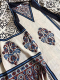 Close-up of oatmeal cotton kurta with blue and red paisley medallion Ajrakh block print, navy blue border stripe, and black geometric Ajrakh dupatta with floral lattice pattern