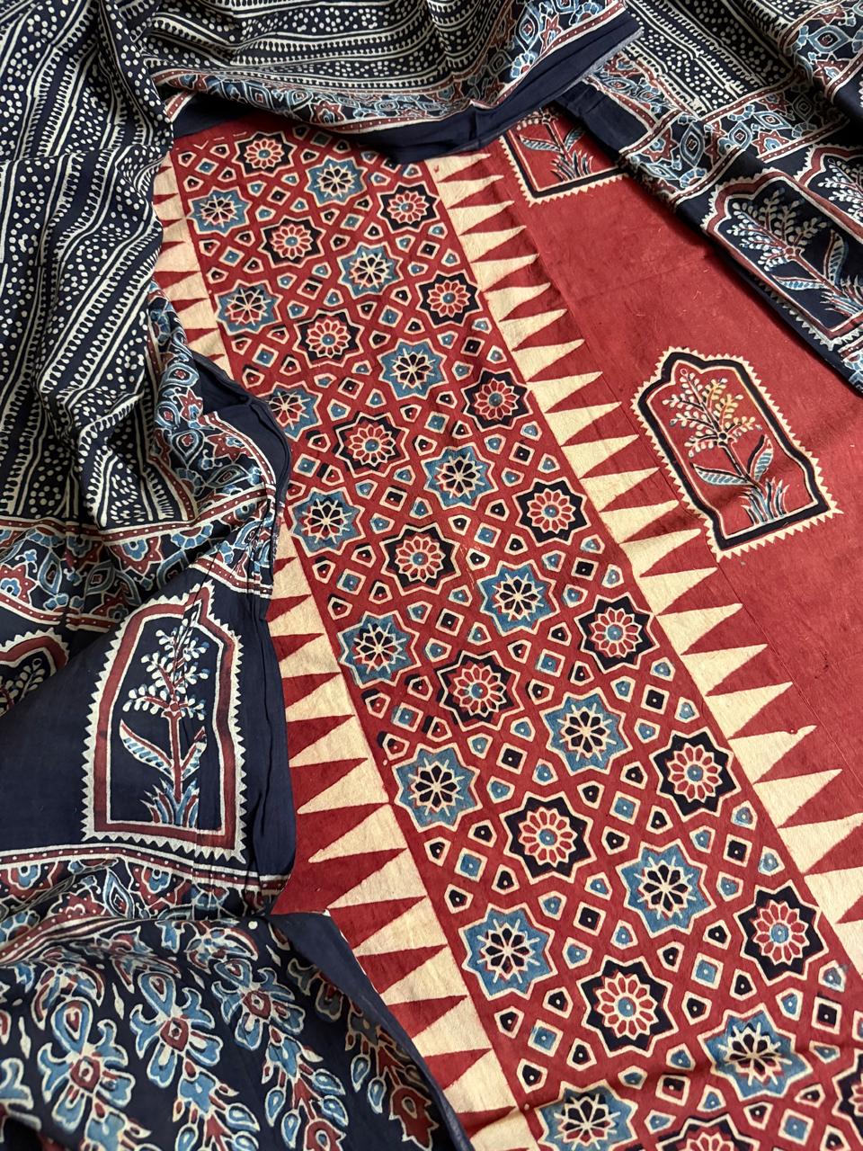 "Close-up of red Ajrakh cotton kurta with geometric star and zigzag border block print, floral arch motif panels, and black Ajrakh dupatta with dense paisley and floral hand block print