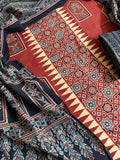 Flat lay of red Ajrakh cotton kurta fabric with geometric star lattice and zigzag border block print, floral arch panels, and black Ajrakh dupatta with paisley and geometric fill motifs