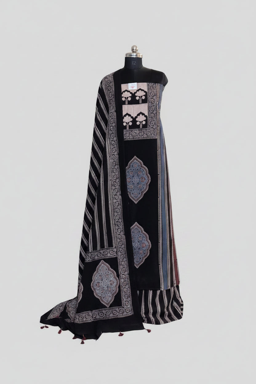 Black and blue Ajrakh cotton 3-piece unstitched suit set on mannequin — deep black kurta with cream tree-of-life panel and indigo blue medallion block print, black dupatta with diagonal stripe and tassel hem