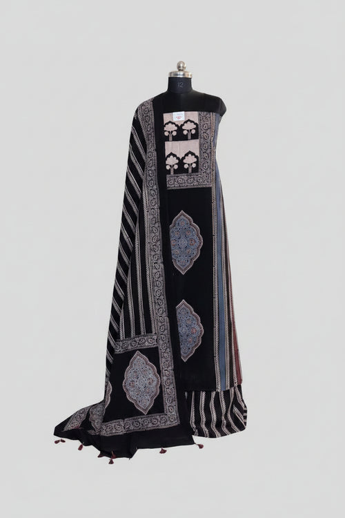 Black and blue Ajrakh cotton 3-piece unstitched suit set on mannequin — deep black kurta with cream tree-of-life panel and indigo blue medallion block print, black dupatta with diagonal stripe and tassel hem
