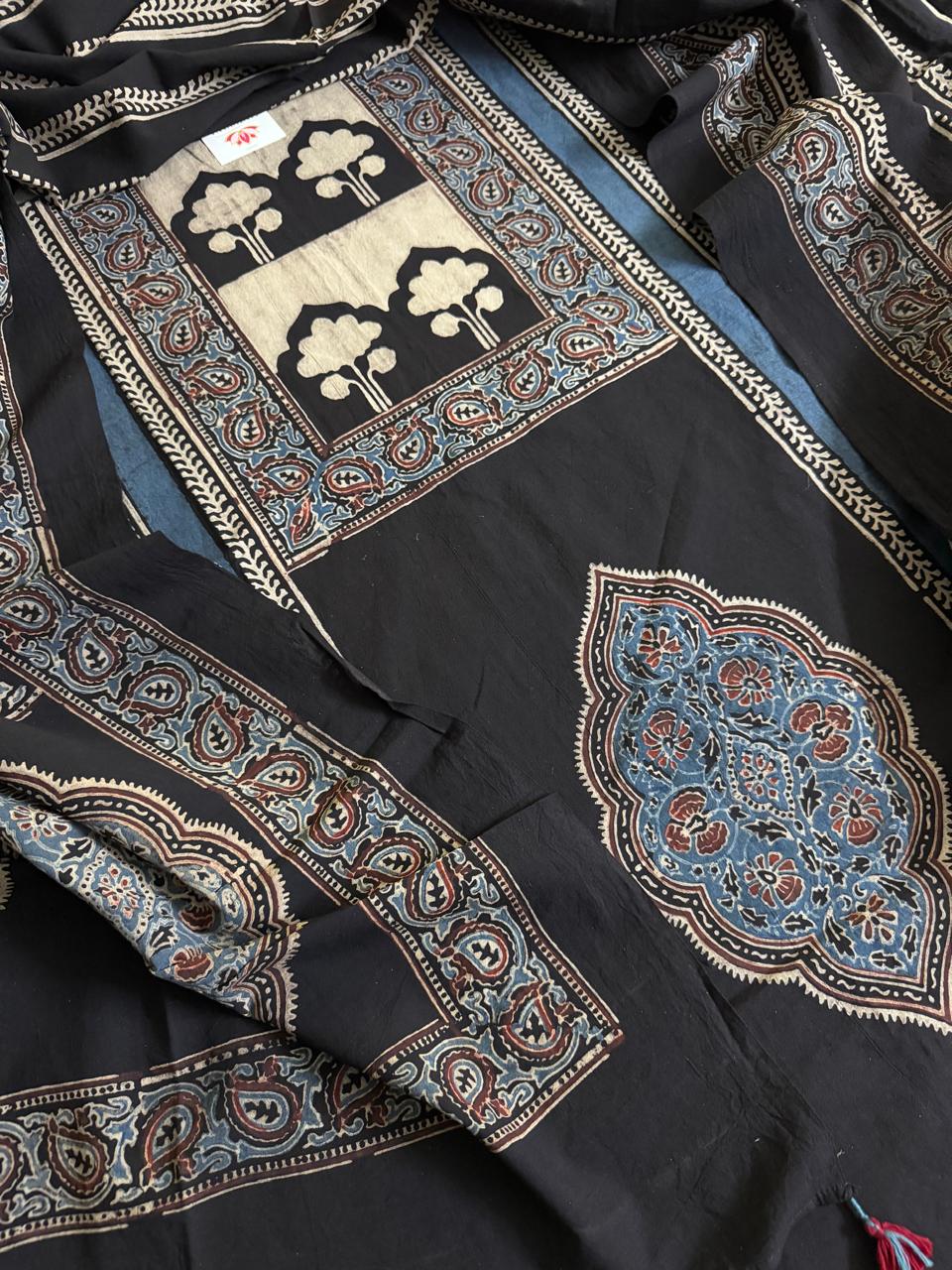 Close-up flat lay of black Ajrakh cotton kurta with cream tree-of-life block print, indigo blue floral medallion motif, and blue paisley border dupatta with dense hand block print