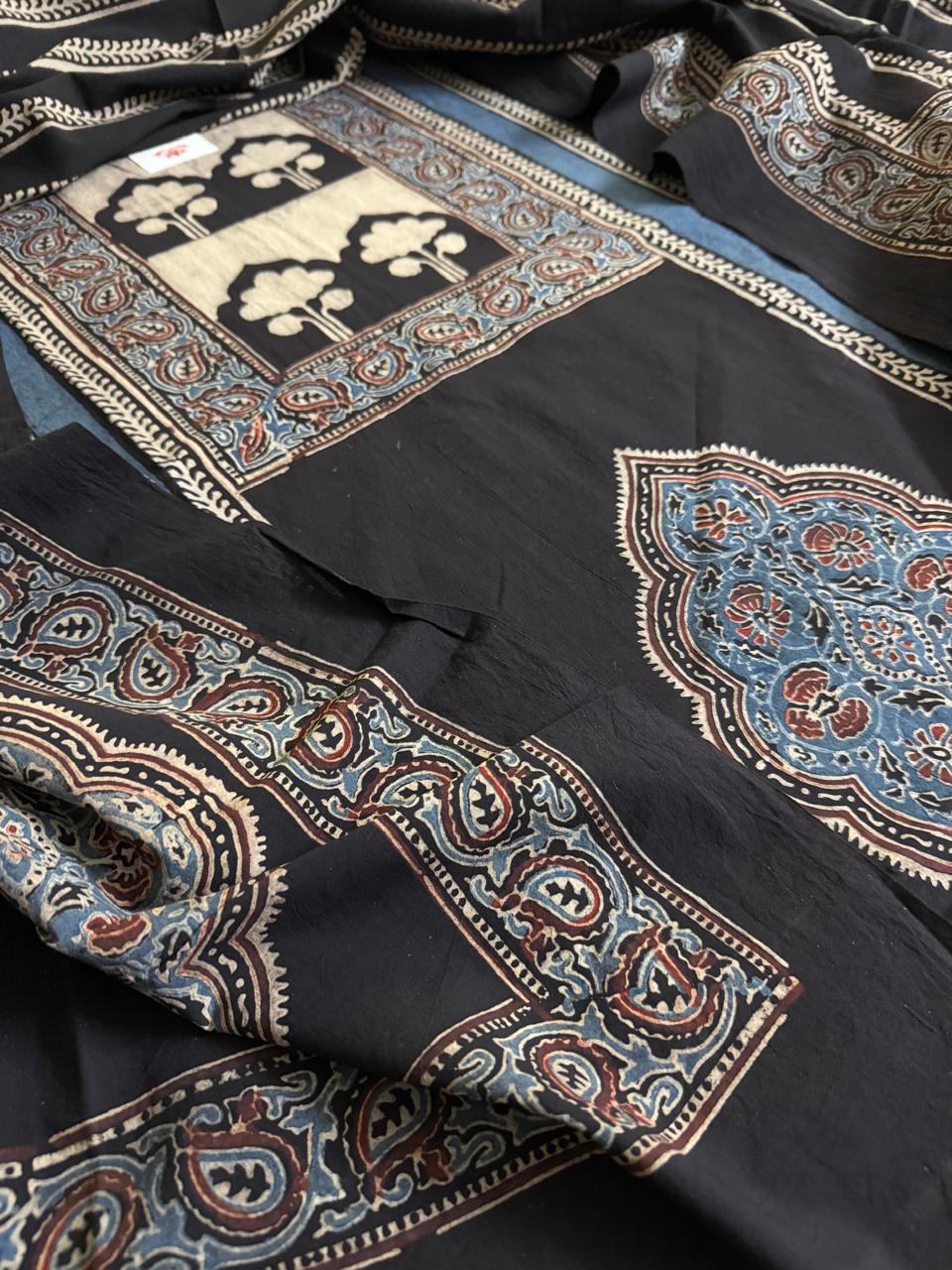 Close-up of black Ajrakh cotton kurta with indigo blue floral medallion hand block print and blue dupatta border featuring large paisley and scrolling floral motifs in indigo and rust tones