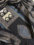 Close-up of black Ajrakh cotton kurta with cream tree-of-life block print panel, indigo blue medallion motif, and blue paisley border alongside black dupatta with diagonal stripe and paisley print