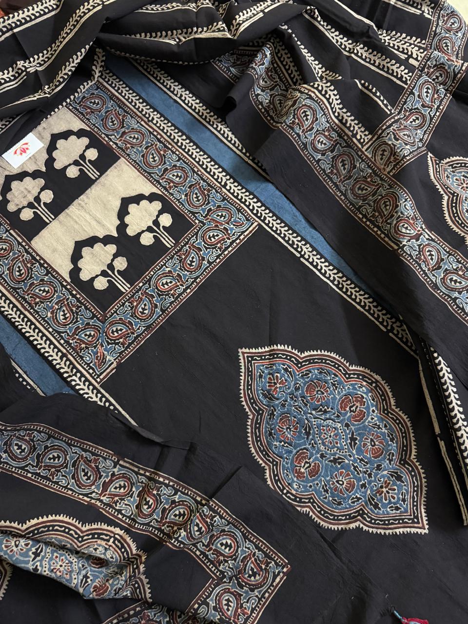 Close-up of black Ajrakh cotton kurta with cream tree-of-life block print panel, indigo blue medallion motif, and blue paisley border alongside black dupatta with diagonal stripe and paisley print