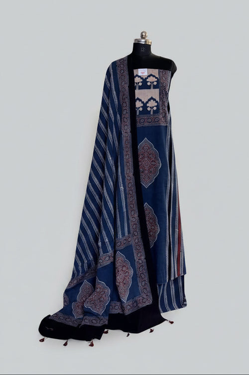 Blue and black Ajrakh cotton 3-piece unstitched suit set on mannequin — indigo blue kurta with cream tree-of-life panel and red medallion block print, blue dupatta with diagonal stripe and tassel hem