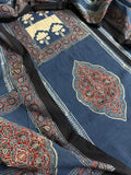 Close-up flat lay of indigo blue Ajrakh cotton kurta with cream tree-of-life block print panel, red floral medallion motif, and blue dupatta with dense red paisley border print