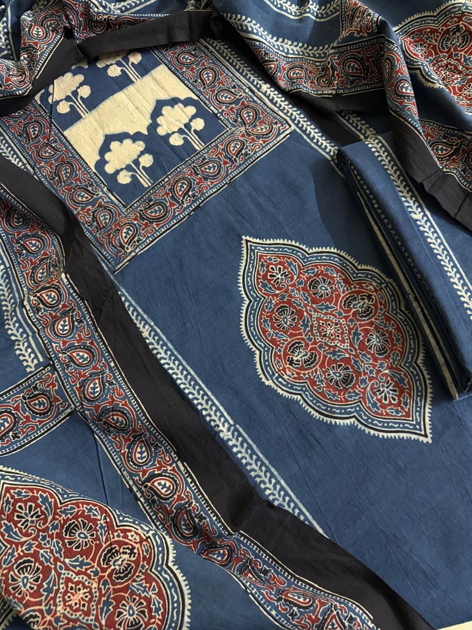 Close-up of indigo blue Ajrakh cotton kurta with cream tree-of-life block print at neckline, large red floral medallion motif, and red paisley border with scrolling vine hand block print
