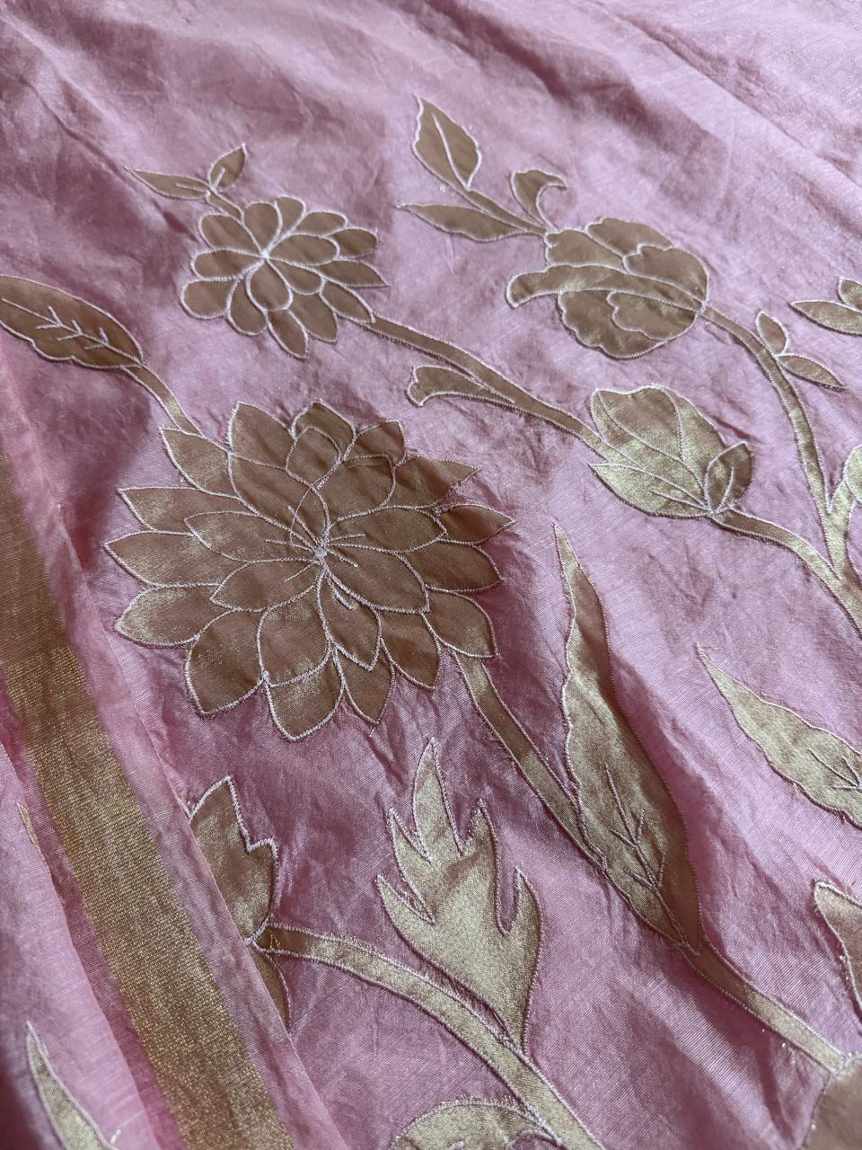 Close-up of pink Chanderi silk fabric with large gold appliqué dahlia flower, bud and leaf motifs in intricate detail