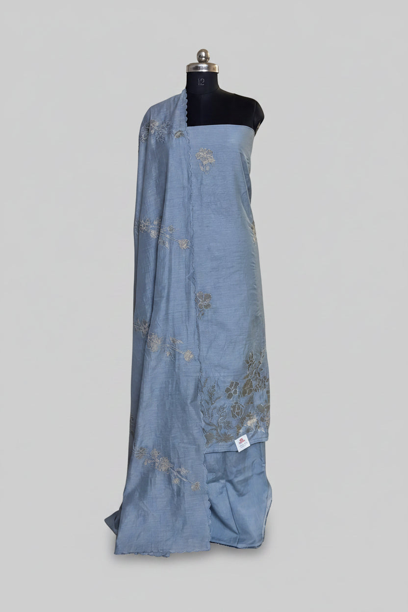 Grey Chanderi silk 3-piece unstitched suit set displayed on mannequin with gold appliqué floral dupatta draped over shoulder