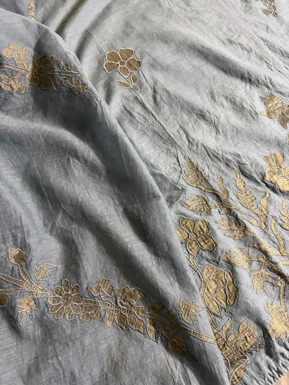Close-up of grey Chanderi silk kurta fabric with gold appliqué floral border and scattered botanical motifs