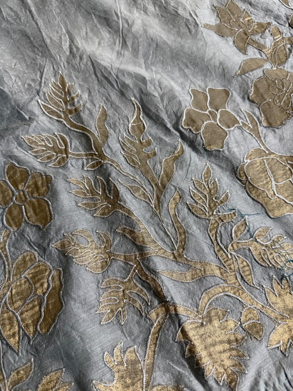 Macro close-up of grey Chanderi silk fabric with large gold appliqué rose, bud and leaf motifs in intricate detail