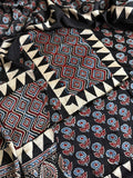 Flat lay of black modal silk Ajrakh kurta dupatta set showing red and blue geometric diamond yoke, floral body print and triangle border pieces