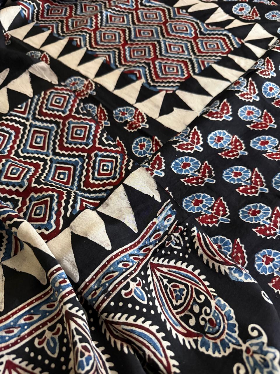 Macro close-up of black Ajrakh modal silk dupatta with large red and blue paisley, geometric diamond and floral block print border detail