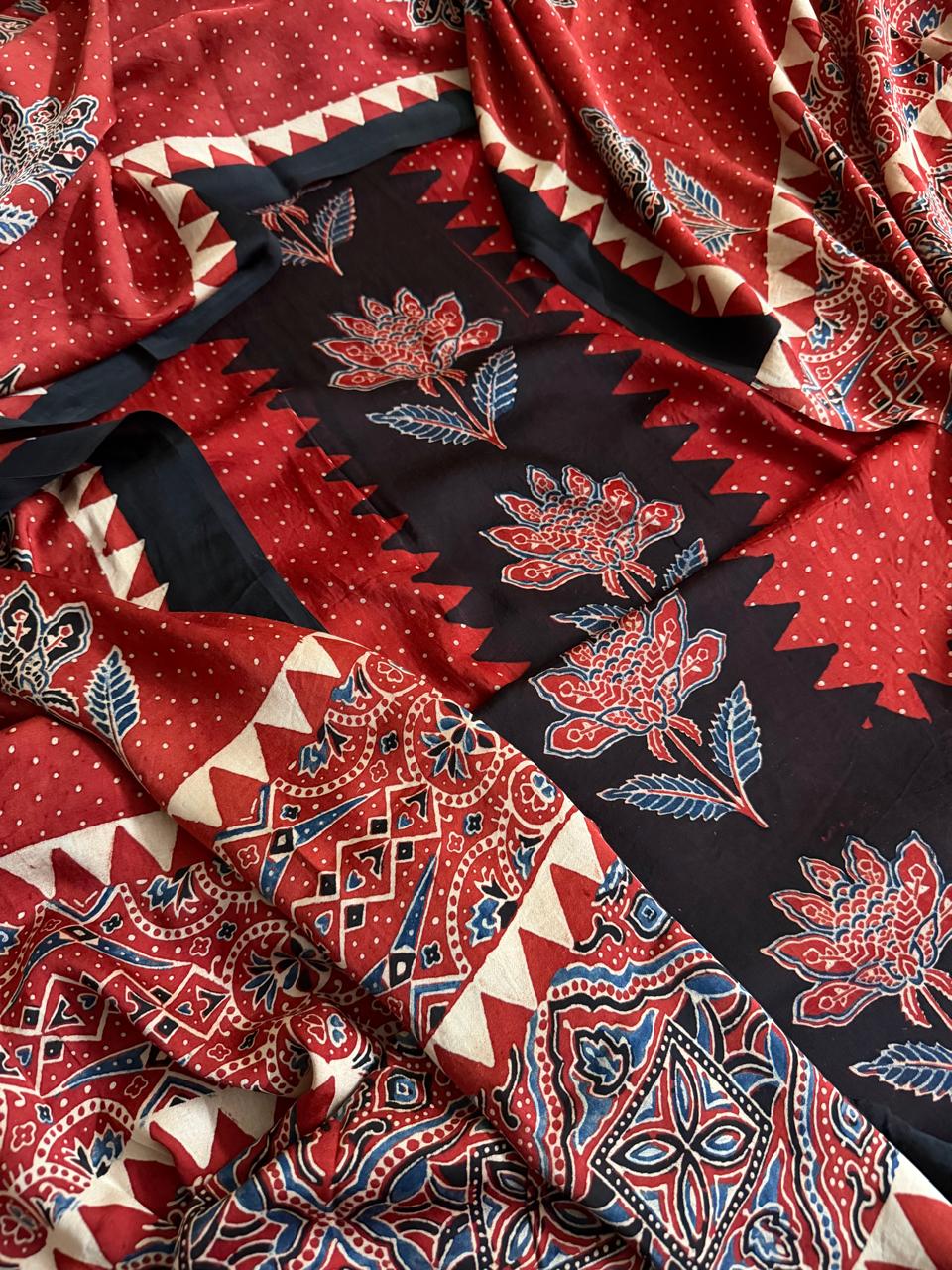 Flat lay of red and black Ajrakh Modal silk kurta dupatta set showing red polka dot body, black zigzag floral panel, and red paisley dupatta border