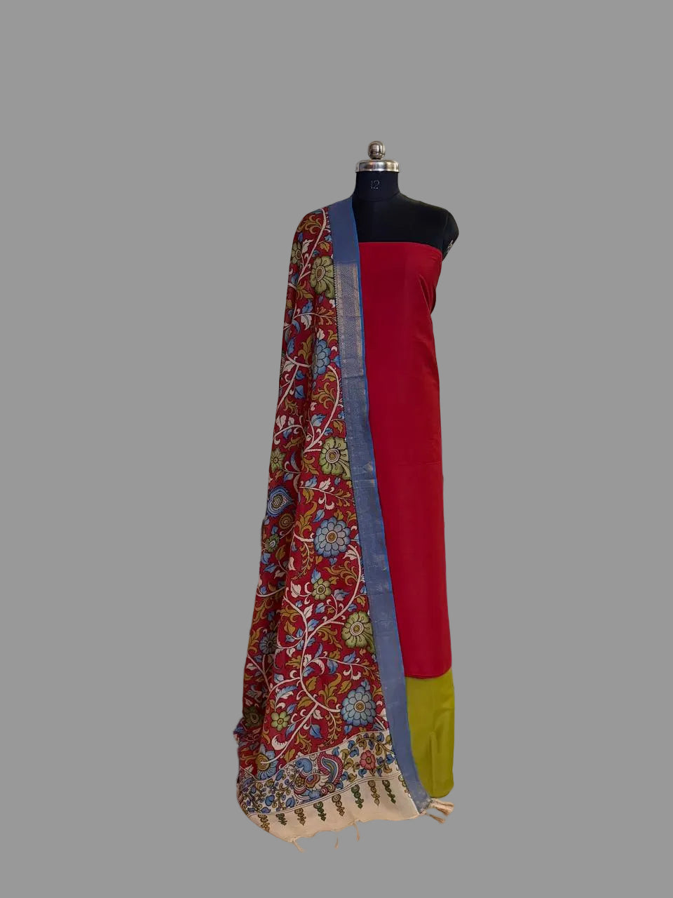Mannequin display of 3-piece unstitched suit set – crimson red cotton silk kurta with hand pen Kalamkari dupatta draped over shoulder, fresh green cotton silk bottom