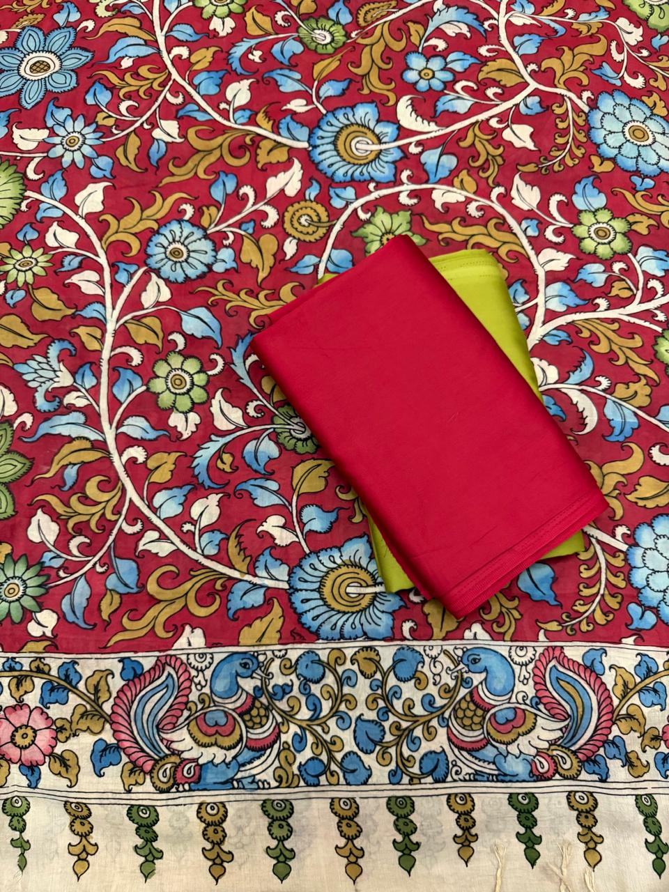 Flat lay of hand pen Kalamkari dupatta spread over crimson red and fresh green cotton silk suit fabrics – peacock-motif border, floral vine body, Mangalgiri silk