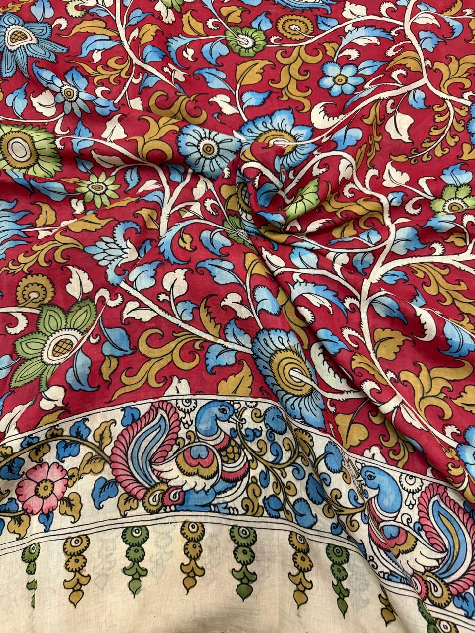 Draped hand pen Kalamkari dupatta showing texture – crimson red floral vine body with ivory peacock-motif border and tassel fringe, Mangalgiri silk drape