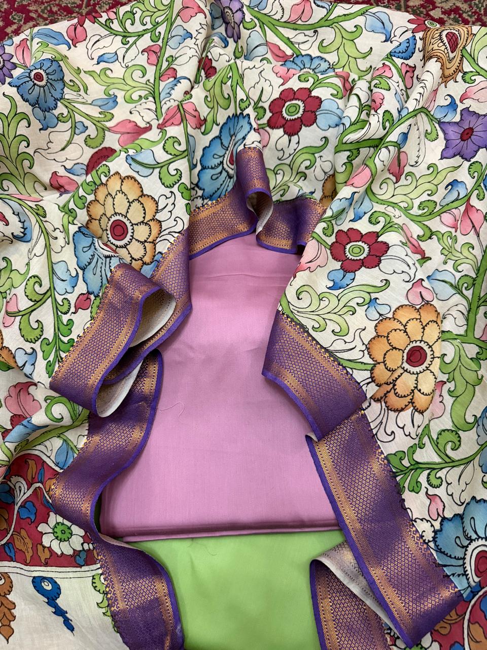 Top-down flat lay of hand pen Kalamkari dupatta framing folded rose pink cotton silk kurta – multicolour floral vine on ivory Mangalgiri silk with purple Zari border and lime green bottom