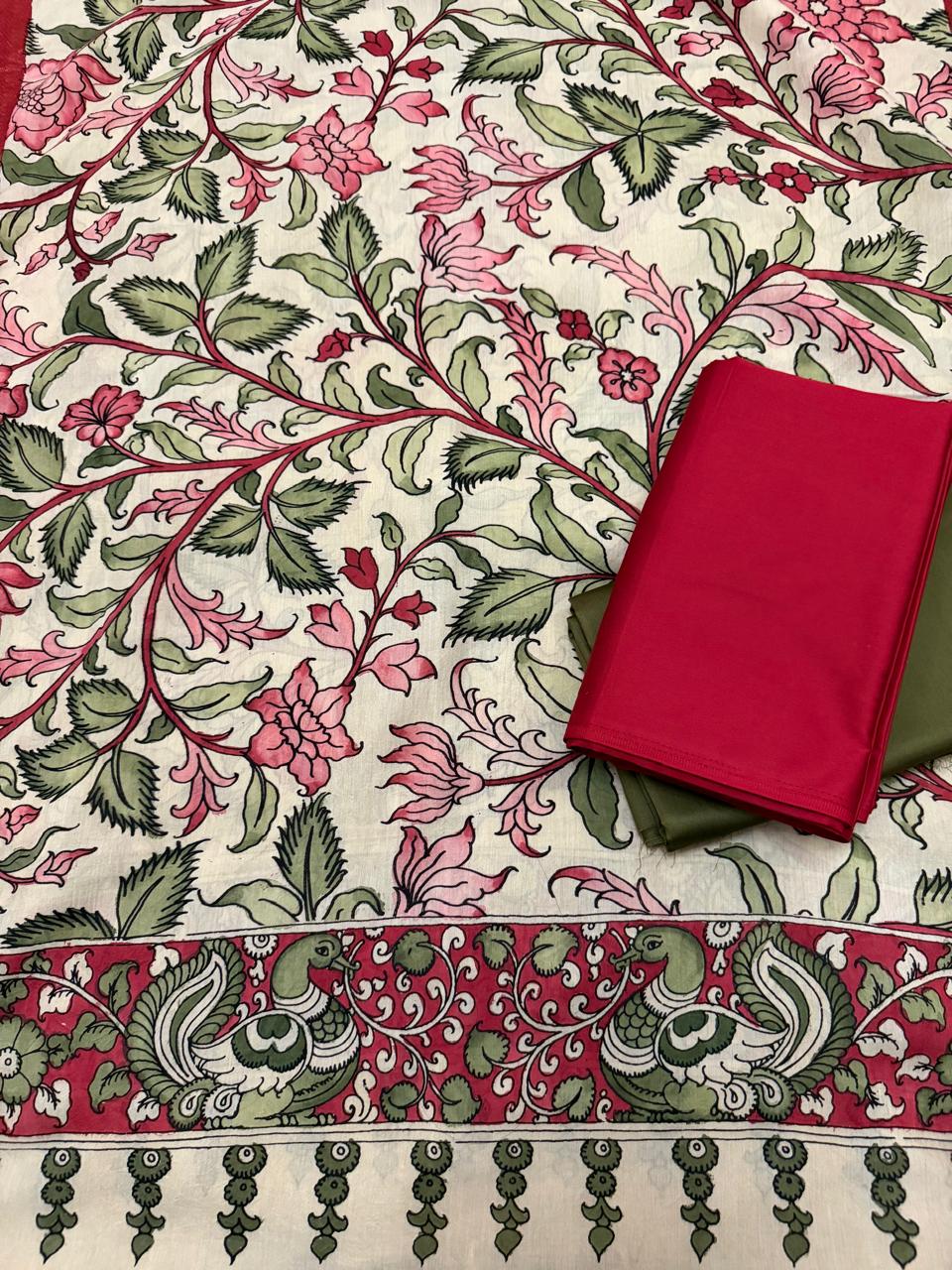 Full spread flat lay of hand pen Kalamkari dupatta showing complete body and peacock-pair border – dense pink and crimson floral vine on ivory Mangalgiri silk, red kurta and forest green bottom alongside