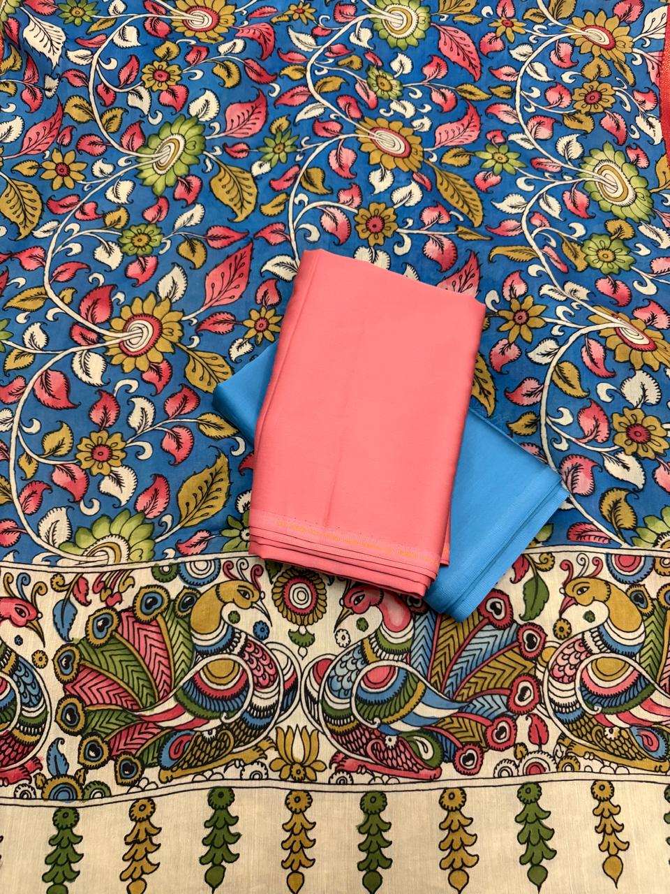 Flat lay of hand painted Kalamkari dupatta pallu and kurta fabric – ivory peacock-pair border with pink and gold plumage on blue ground floral body above, rose pink cotton silk kurta beside