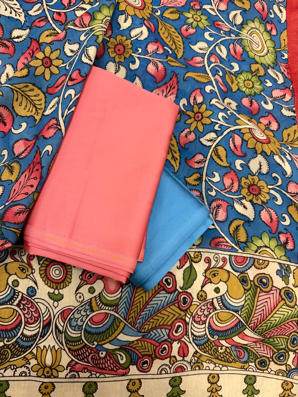 Full spread flat lay of hand painted Kalamkari dupatta over rose pink and slate blue suit fabrics – blue ground dense multicolour floral vine body with ivory peacock-pair pallu and red-gold Zari border