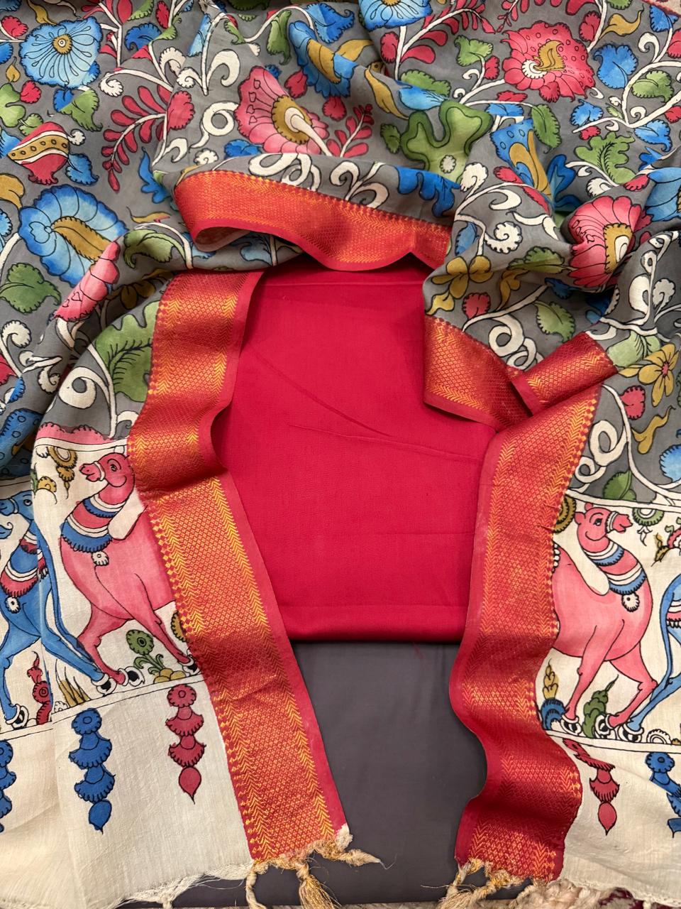 Overhead flat lay of hand painted Kalamkari dupatta wrapped around folded red cotton silk kurta and charcoal grey bottom – ivory mythological border with gopi figures and animal procession visible on pallu
