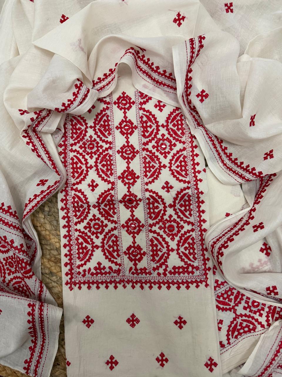 Macro detail of red Sindhi hand embroidery on cream Bengal cotton – geometric diamond lattice with floral and paisley motifs, unstitched kurta fabric