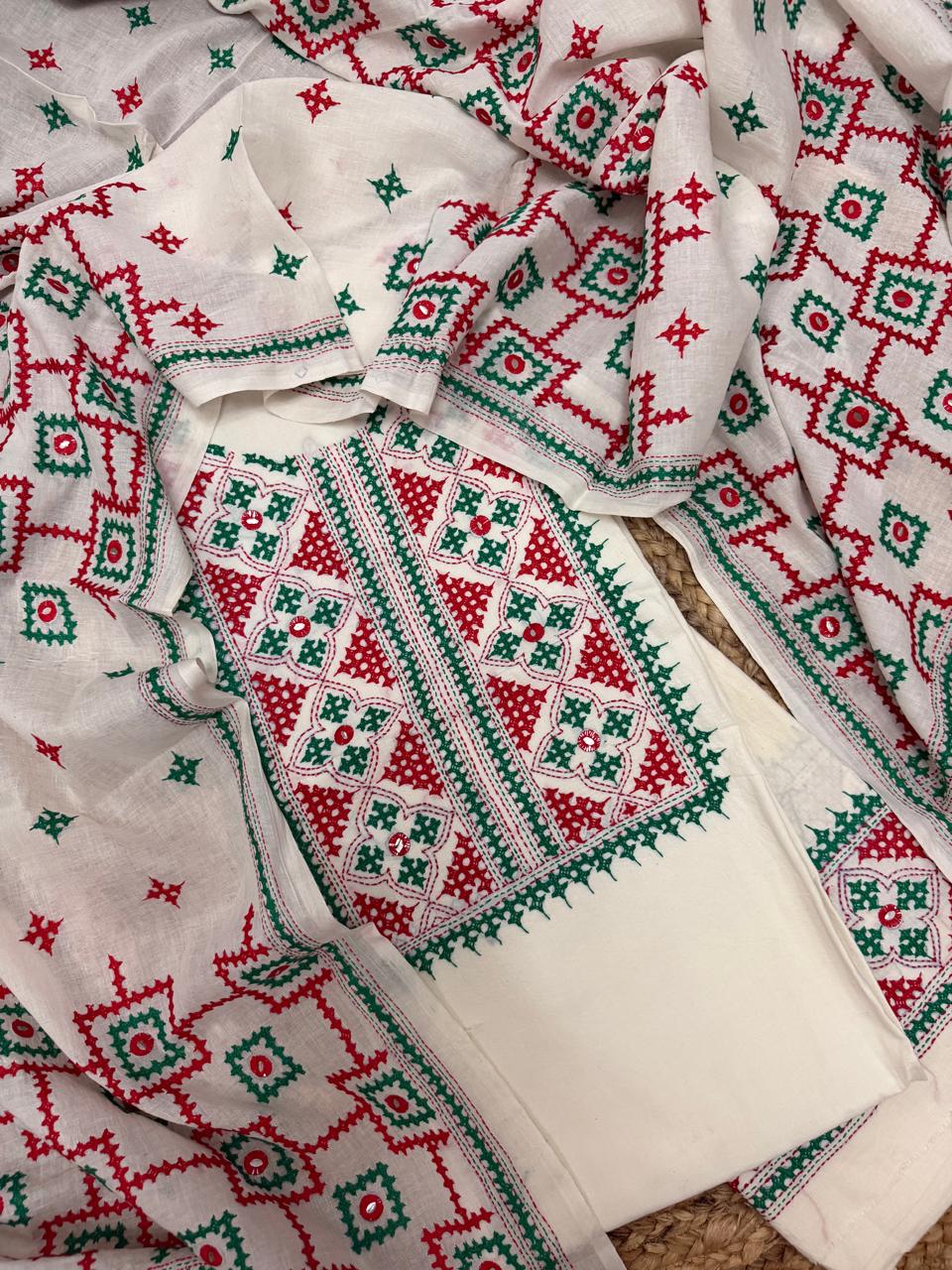 Cream cotton unstitched kurta with dense red and green Sindhi hand embroidery – geometric neckline panel, all-over butti motifs and embroidered dupatta, 3-piece suit set flatlay