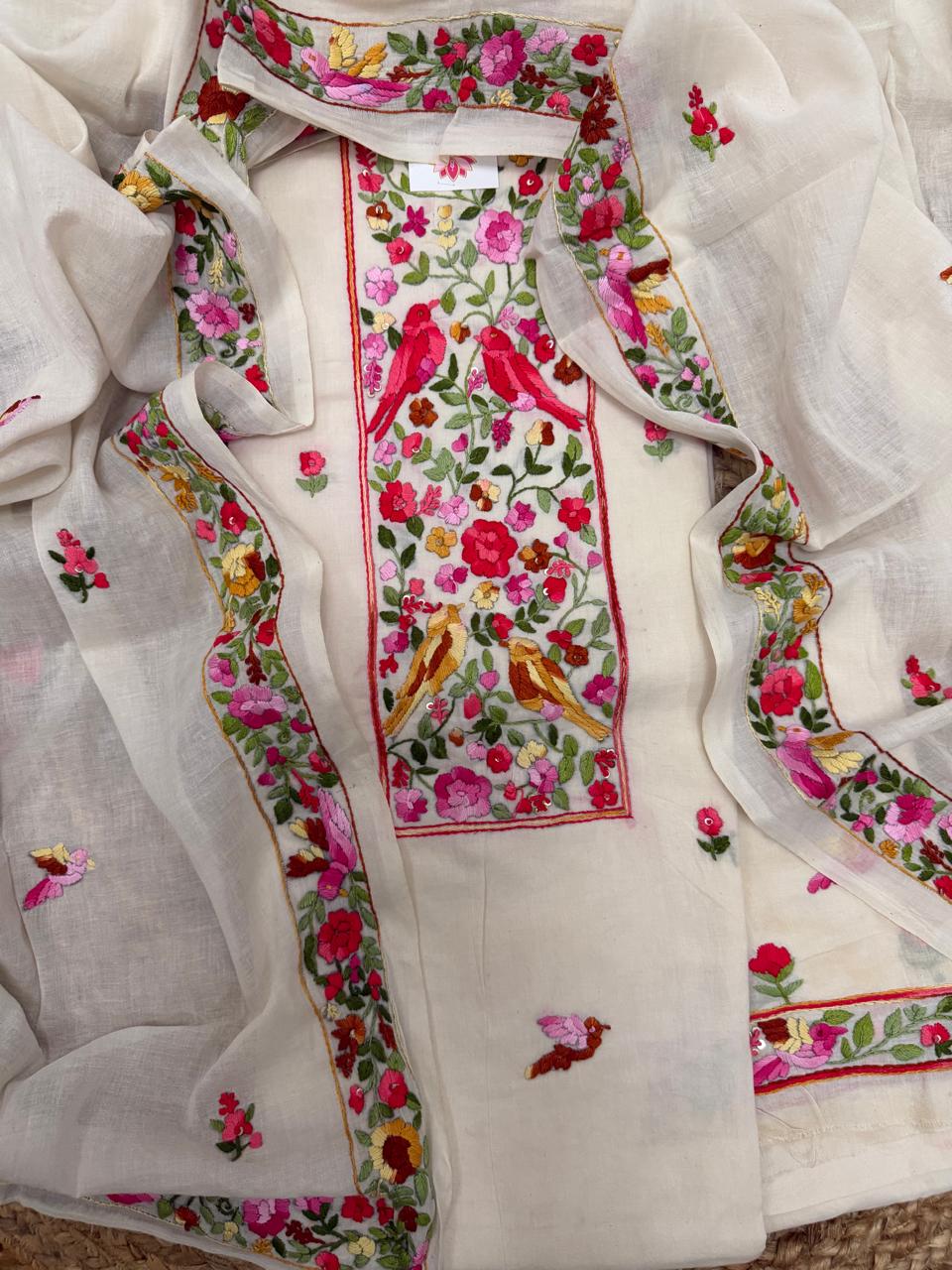 Cream cotton unstitched kurta with Parsi Gara hand embroidery – red and golden bird pair on floral jaal neckline panel, scattered butti body and floral border dupatta, 3-piece suit set flatlay