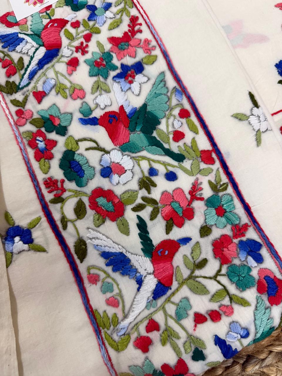 Macro detail of Parsi Gara hand embroidery on cream cotton kurta – red and blue hummingbirds amid dense multicolour floral jaal in red, blue, teal and green threads