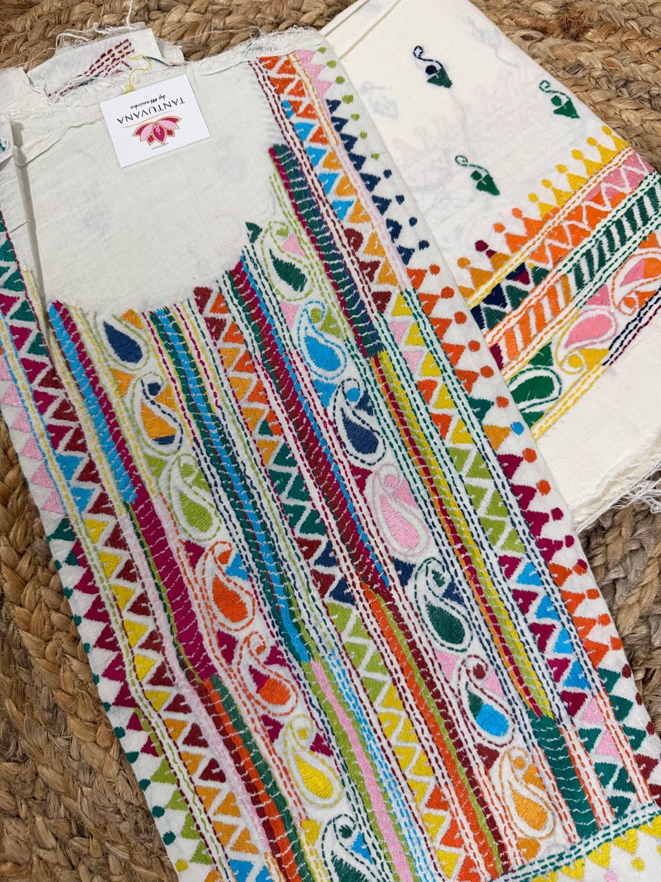 Angled flatlay of white cotton Kantha hand-embroidered unstitched co-ord set – multicolour striped paisley and geometric triangle neckline panel with scattered butti