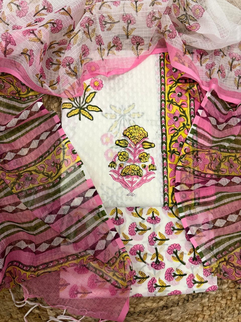 Straight overhead flatlay of white cotton Mughal block print unstitched 3-piece suit set – pink and yellow marigold floral butti kurta with yellow floral vine border strip, pink floral Kota Doria dupatta and pink floral bottom fabric

