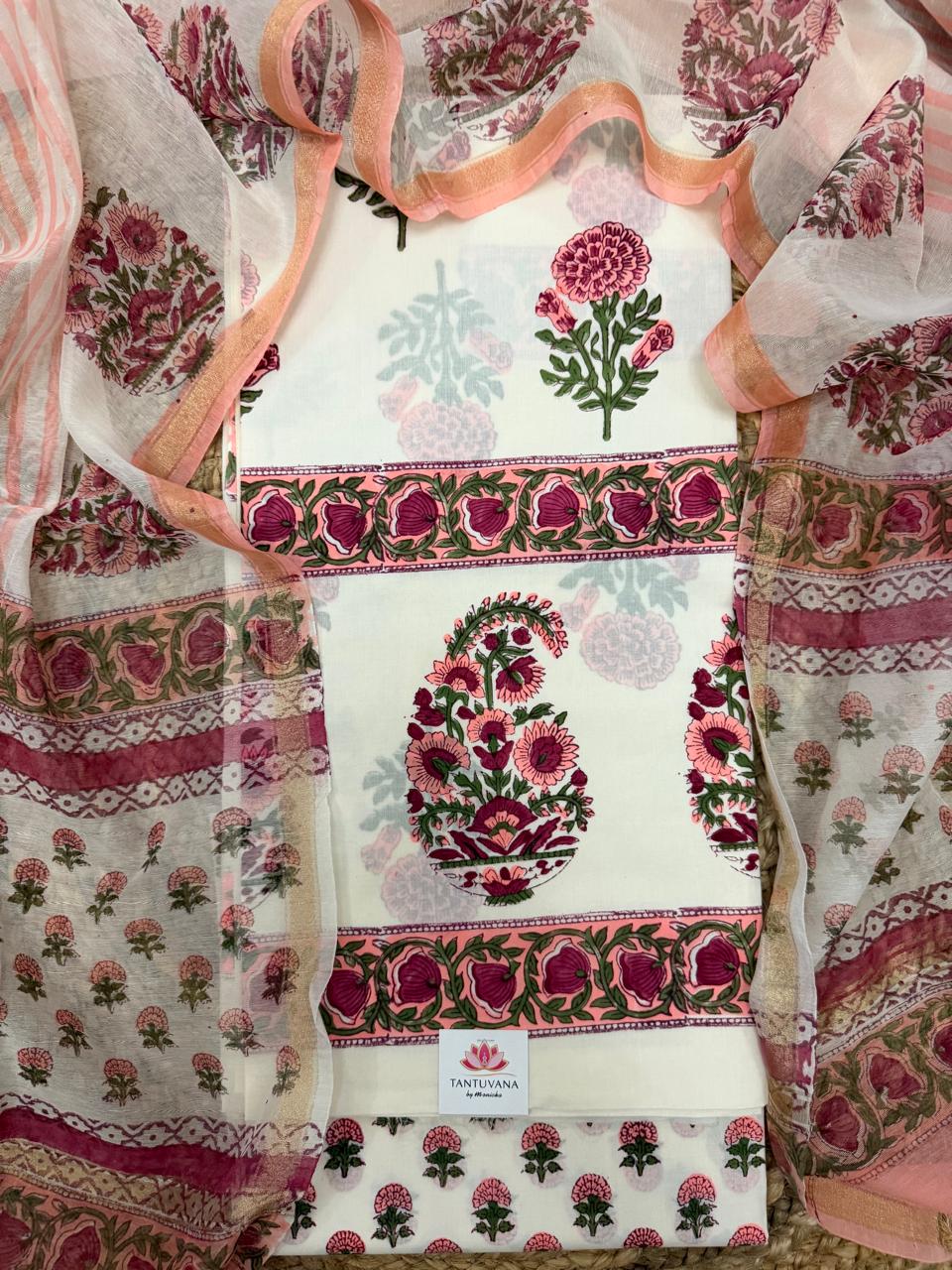 Overhead flatlay of white cotton placement block print unstitched kurta – pink marigold butti top, large paisley floral centre panel with pink floral border, sheer Chanderi dupatta with pink floral border draped around