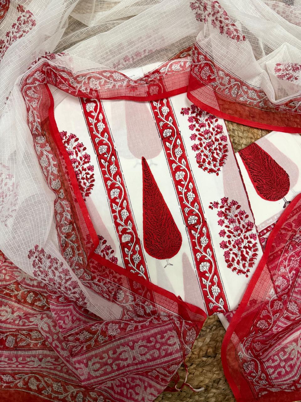Overhead flatlay of white cotton placement block print unstitched kurta – large red paisley teardrop motifs with red floral vine border strips and scattered floral butti, sheer Kota Doria dupatta with red floral border