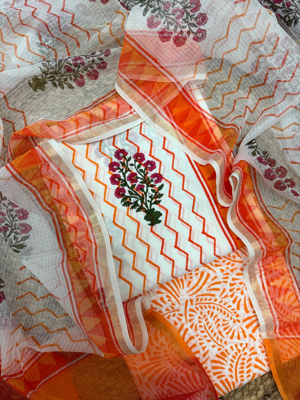 Overhead flatlay of white cotton Mughal block print unstitched kurta – orange zigzag chevron body with pink floral butti placement, orange paisley bottom fabric and sheer Kota Doria dupatta with orange chevron and border draped around