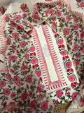 Angled overhead flatlay of white cotton placement floral block print unstitched kurta – pink dahlia and red tulip vine border strip with red scallop edge, Chanderi silk dupatta with pink rose and green leaf all-over print draped 