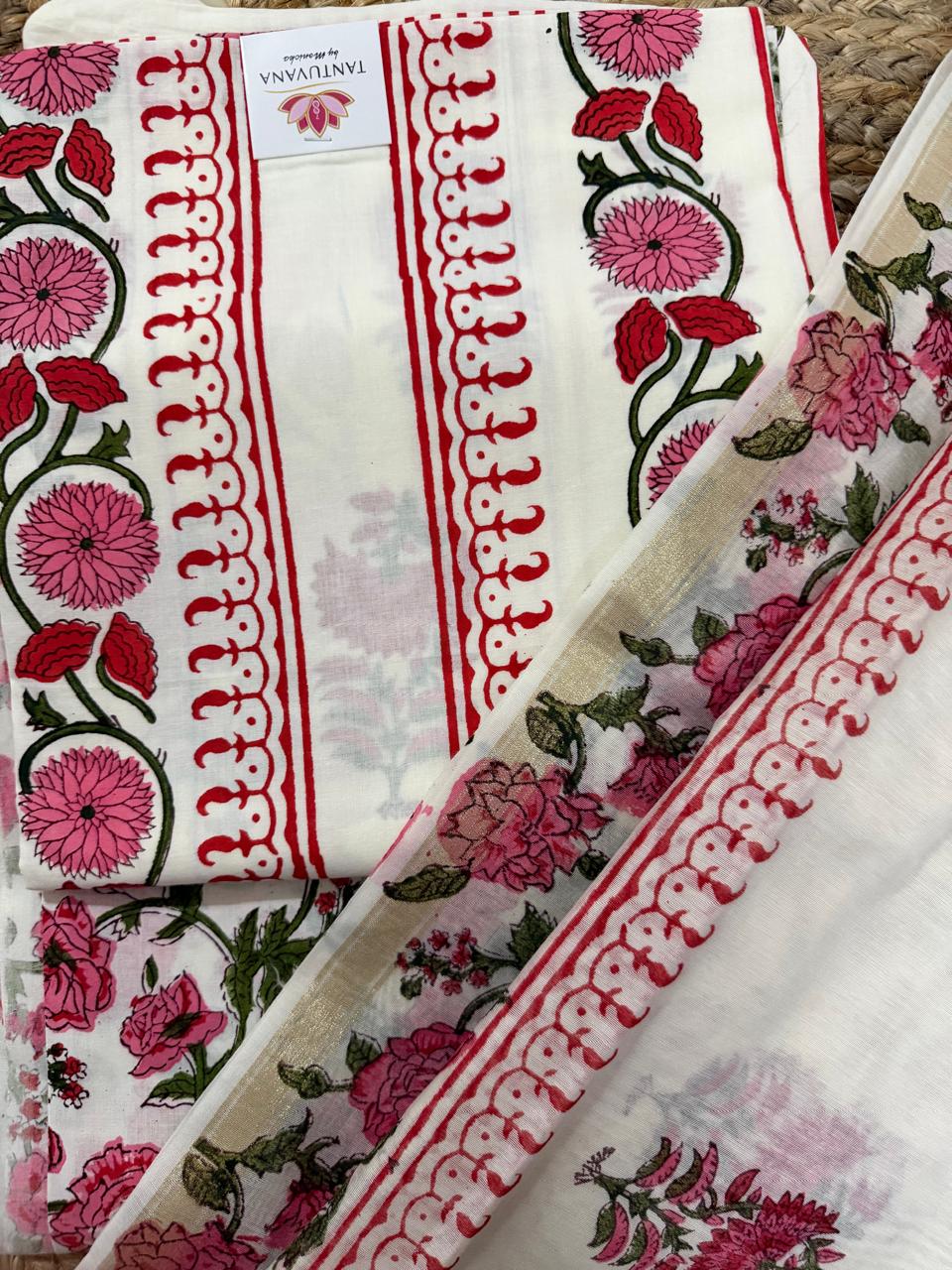 Straight flatlay of white cotton placement floral block print unstitched kurta – pink dahlia and red tulip vine border strip with red scallop edge, folded with Tantuvana tag, sheer Chanderi dupatta with red scallop border draped around and pink rose bottom fabric visible 