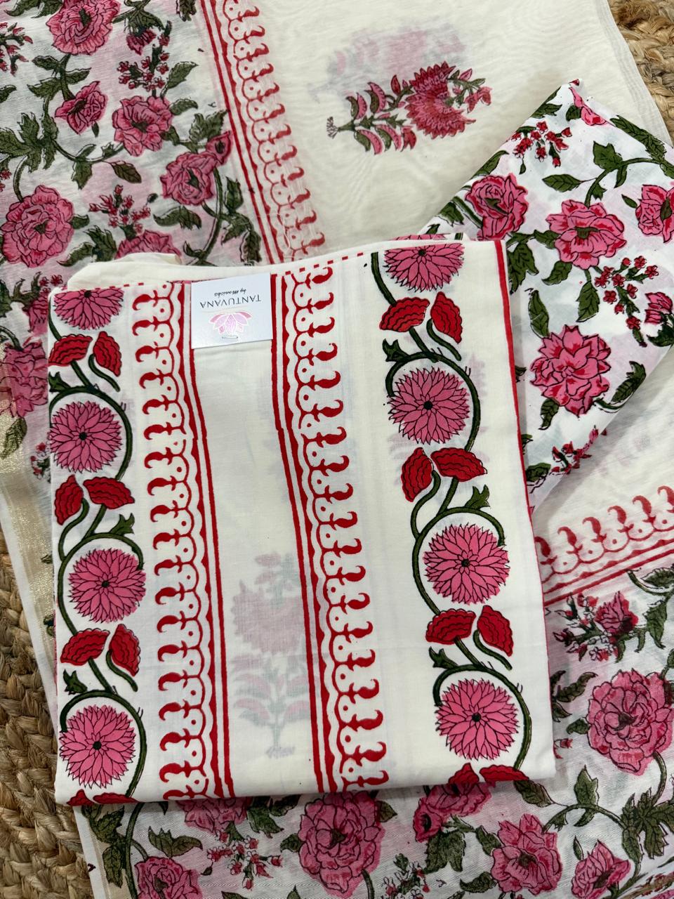 Angled flatlay of white cotton placement floral block print unstitched kurta – pink dahlia and red tulip vine border strip with red scallop edge, folded with Tantuvana tag, sheer Chanderi dupatta with red scallop border and pink rose bottom fabric layered 