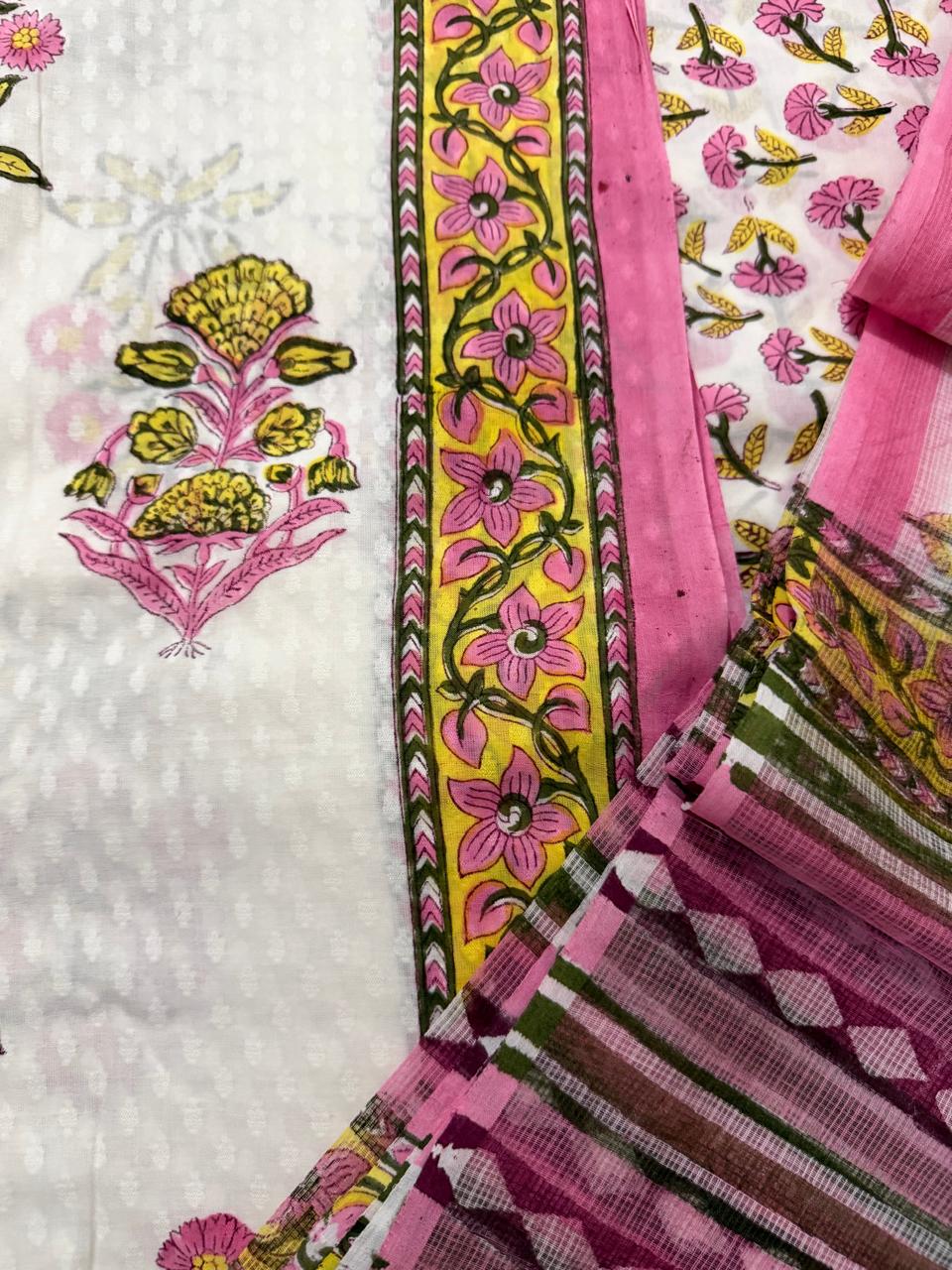Macro close-up of white cotton Mughal block print kurta – yellow floral vine border strip with pink marigold butti, alongside sheer Kota Doria dupatta showing pink floral butti and pink-olive stripe weave border detail
