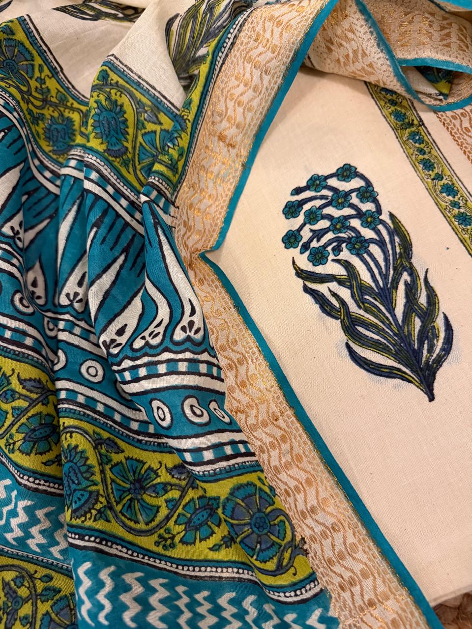 Close-up of teal block print dupatta with bold green-yellow floral and geometric border alongside cream cotton kurta fabric with teal-blue floral bouquet block print motif and golden border
