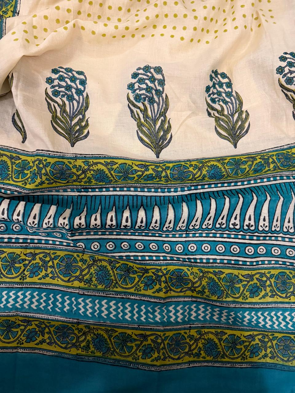 Close-up flat lay showing cream cotton dupatta with repeated teal-green floral bouquet block print motifs and bold green-yellow geometric stripe, white teardrop, and floral vine patterns, with cream polka dot