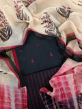 Flat lay of black and red handloom cotton 3-piece unstitched suit set with Kota Doria dupatta showing block print floral motifs, red anchor embroidery on kurta fabric, and striped bottom