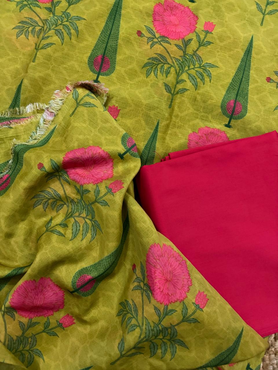 Close flat lay of lime green Malai Chanderi silk fabric with pink peony block print and green cypress motifs, paired with folded solid hot pink Malai Chanderi bottom fabric