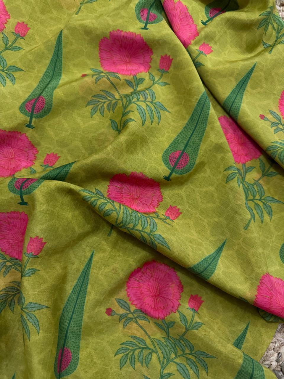 Close-up draped detail of lime green Malai Chanderi silk fabric showing large pink peony blooms, green cypress motifs, and delicate honeycomb texture of the silk weave