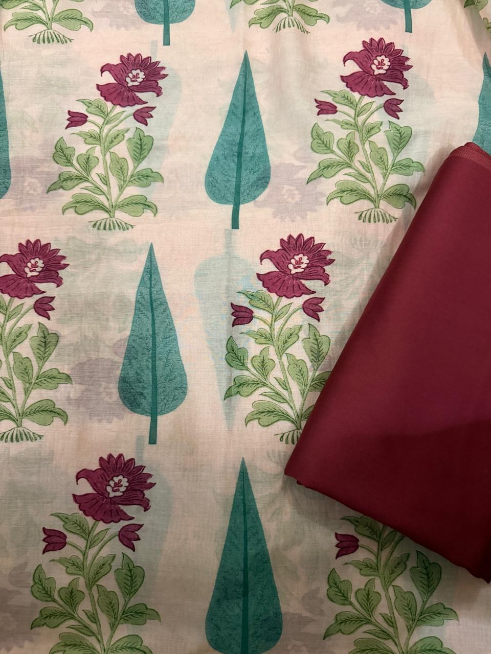 Flat lay of cream Malai Chanderi silk kurta fabric with teal cypress leaf and plum floral block print, with folded solid plum Malai Chanderi bottom fabric placed at bottom right corner