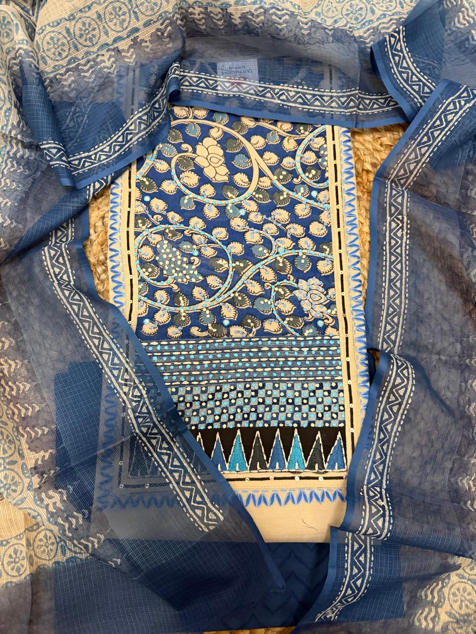 Taupe and blue 3-piece unstitched suit set – overhead flat lay showing blue block print patched neckline with floral vine and lotus motifs, Kota Doria dupatta with chevron border